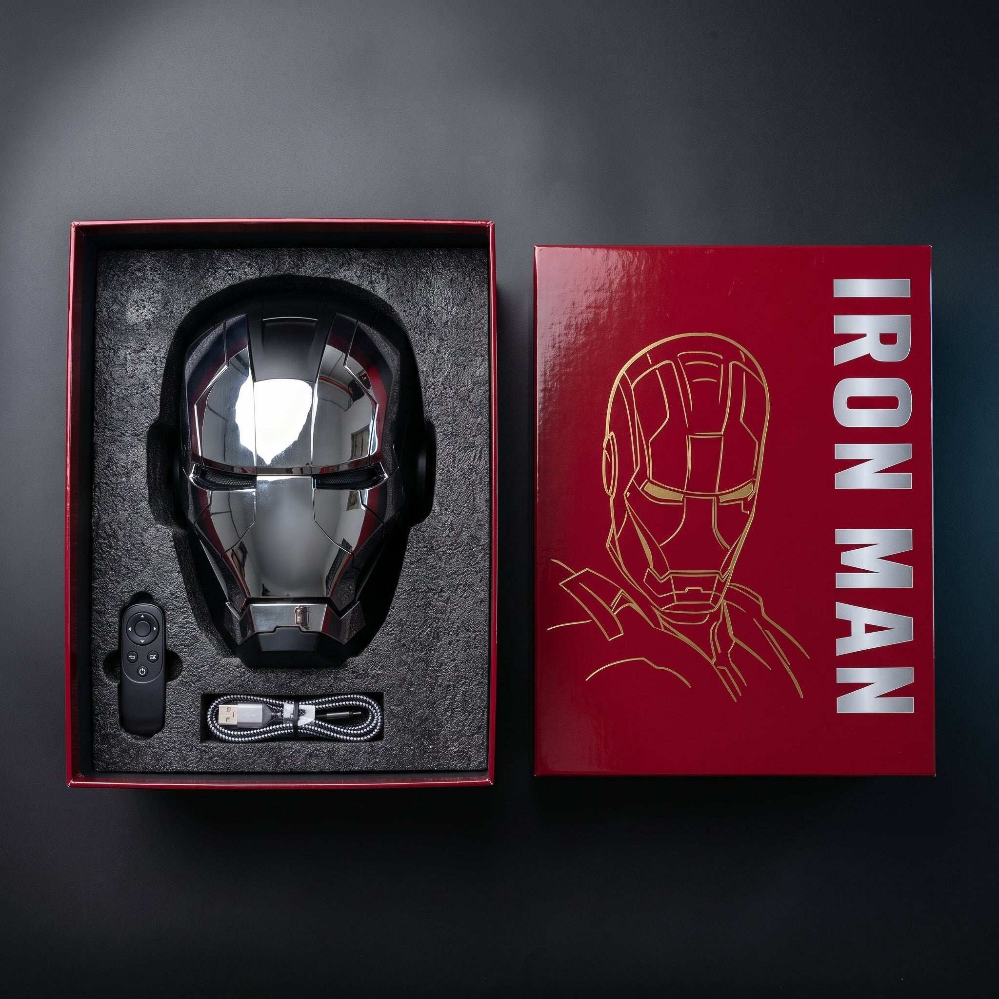 Black and silver Mark V helmet in its open box with remote control and USB charging cable